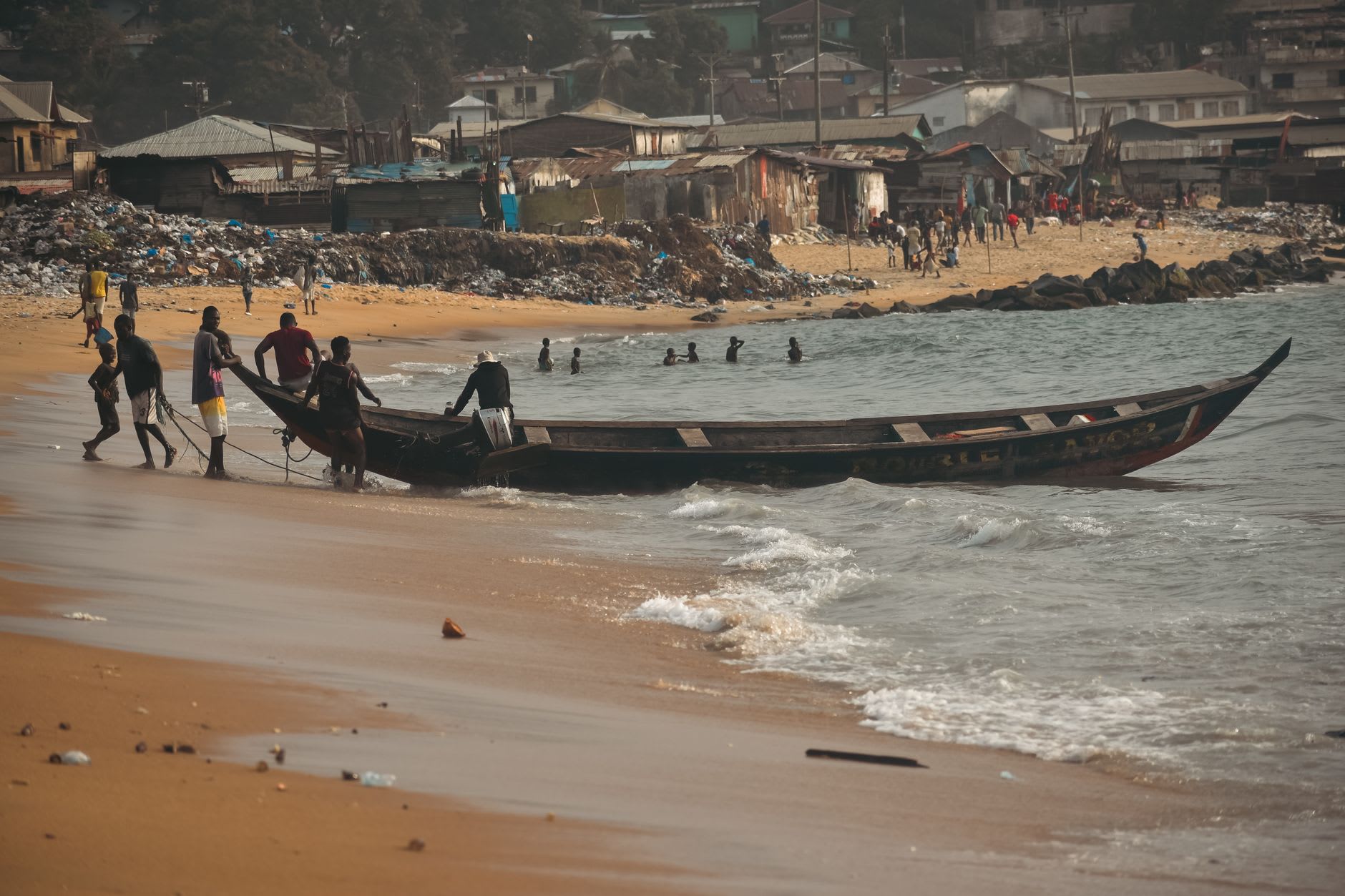 Gbarnga's central market, produce sellers and tailors under canvas awnings, the Bong Range hills in the background