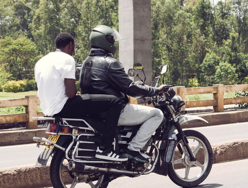 A motorbike taxi passing a roadside rubber stall near Kakata, Liberia