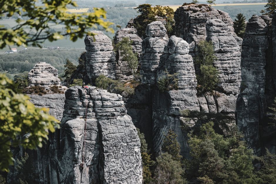 Climber on a bolted sandstone route near Berdorf with forest below