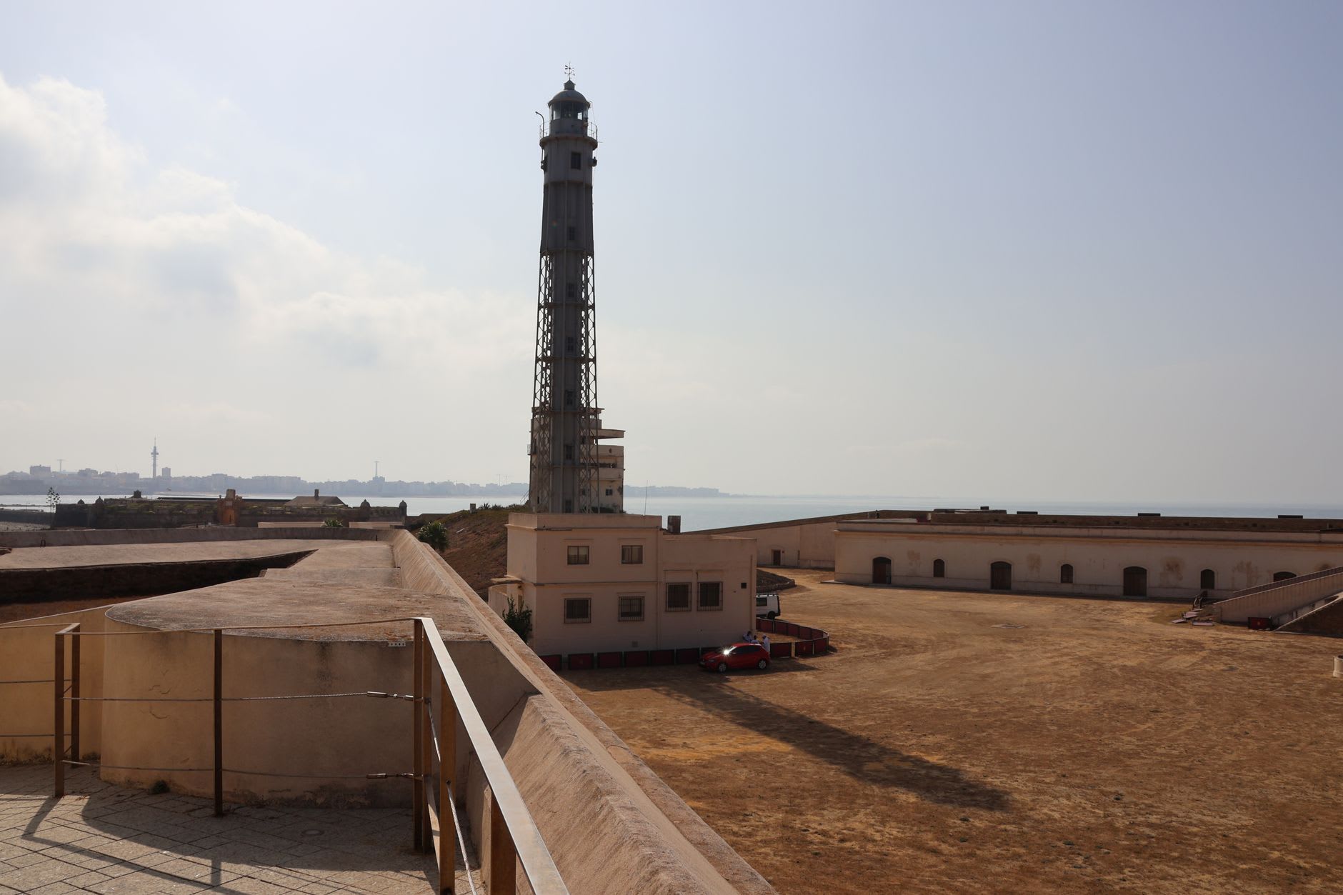 The white cylindrical lighthouse of Guia standing above the fortress walls, the city of Macau spreading to the horizon below through the summer haze