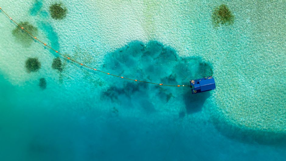Una vista a nivel aéreo del banco de arena turquesa poco profundo del Mar Esmeralda, con la arena visible a través de un agua imposiblemente clara
