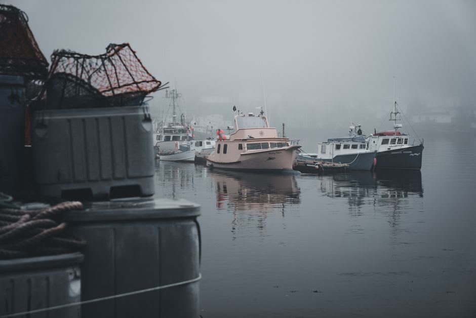 Fishing boats and lobster traps stacked on the dock at Boothbay Harbor in early morning light