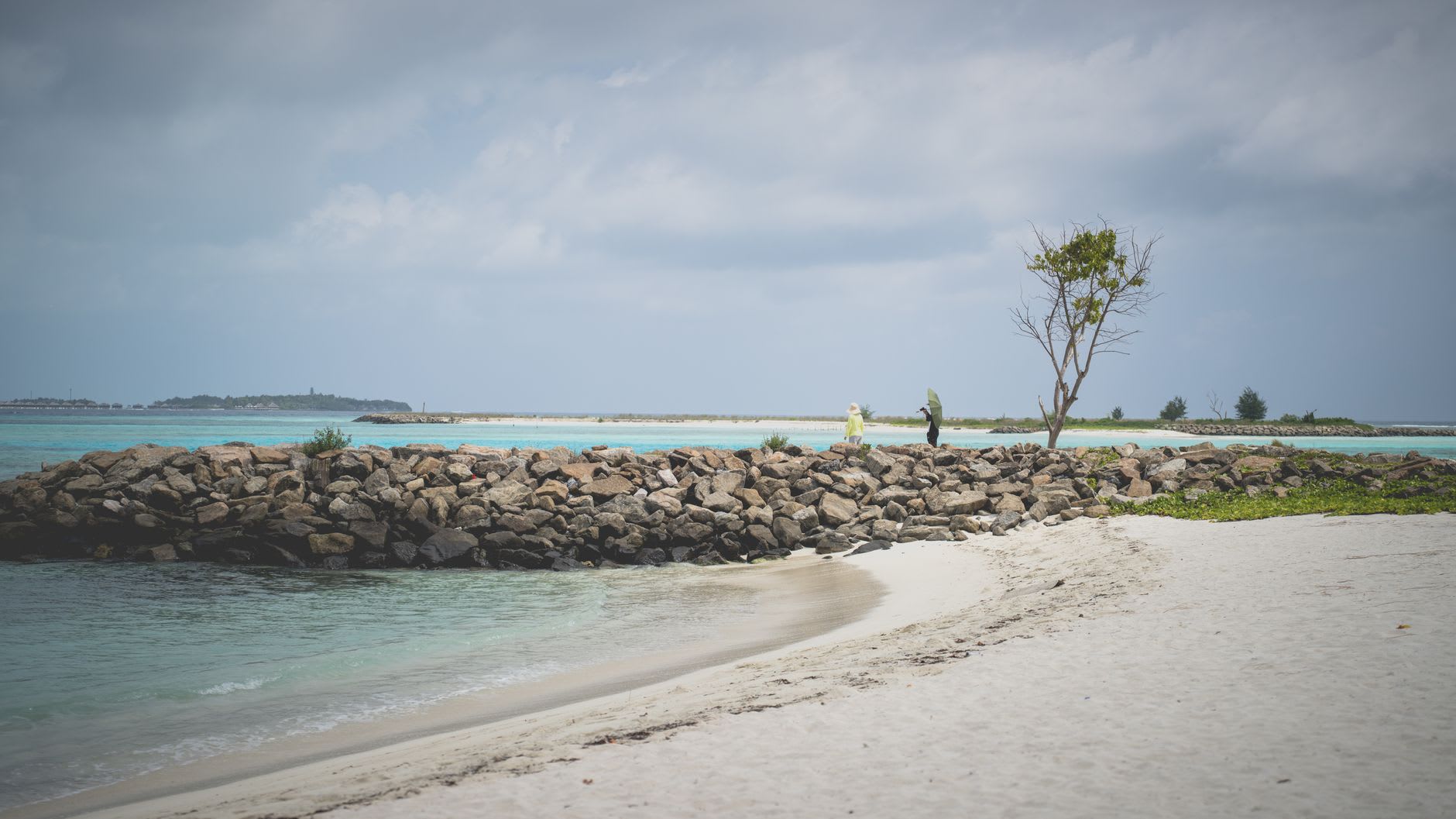 Bicicletas locales aparcadas frente a un alojamiento de Maafushi, barcos pesqueros en el puerto detrás