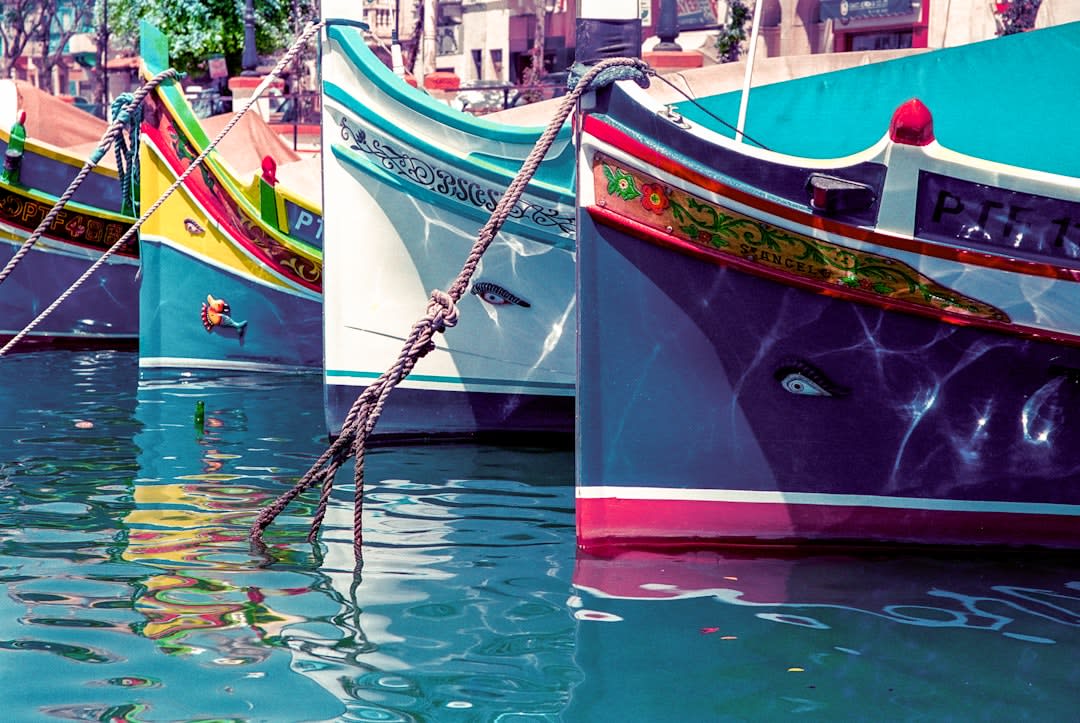 Close-up of a traditional Maltese luzzu boat painted in bright blue and yellow with eyes on the bow