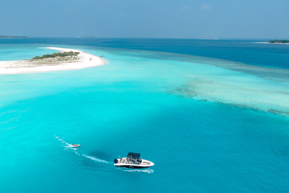 The wide, undeveloped lagoon of Enewetak Atoll seen from a boat, with a low, narrow islet in the distance