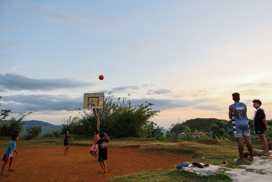 Des enfants jouant au basket sur un terrain extérieur fissuré au crépuscule sur l'îlot principal d'Utrik