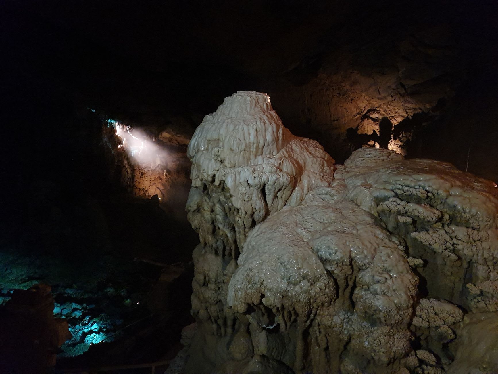 Stalactite and stalagmite formations in Mawsmai Cave meeting in a column, lit to show the calcite's natural amber colour
