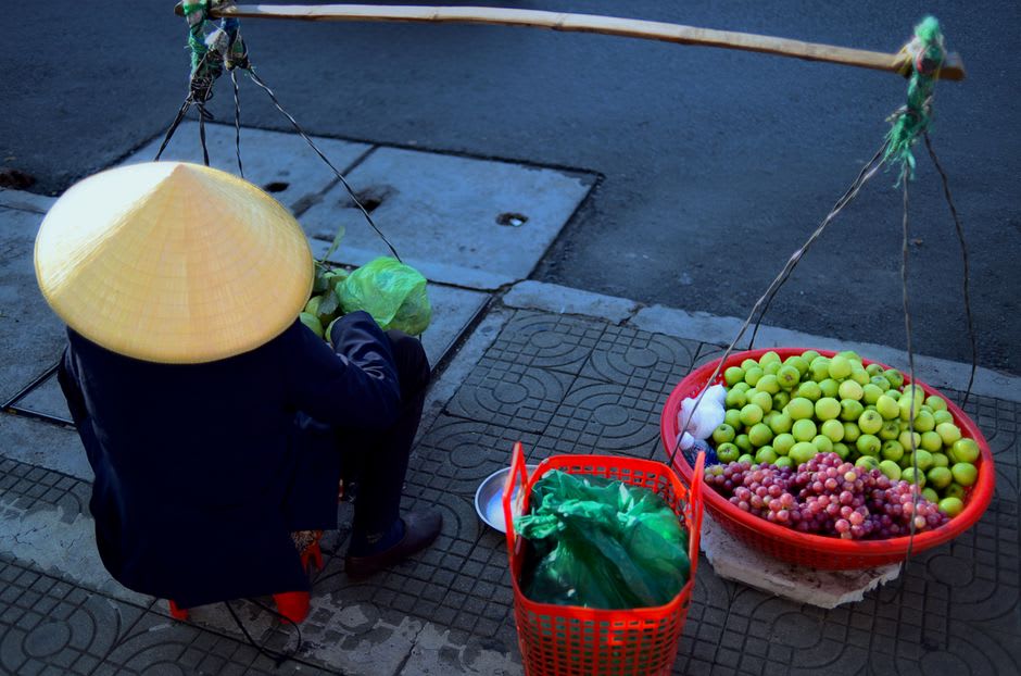 Bamboo poles hung with pineapples and squash marking vendor boats at Cai Be floating market