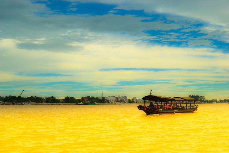 The twin-towered facade of Cai Be Catholic Church seen from the river at dawn