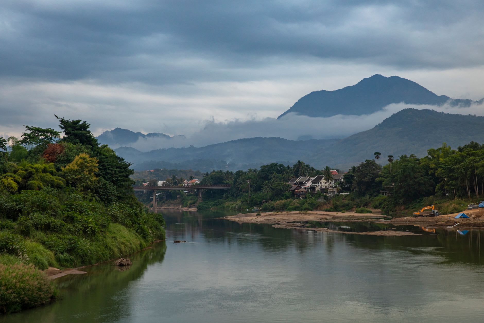 El río Nam Song en Vang Vieng con kayakistas y puentes colgantes de bambú, acantilados de caliza reflejados en el agua