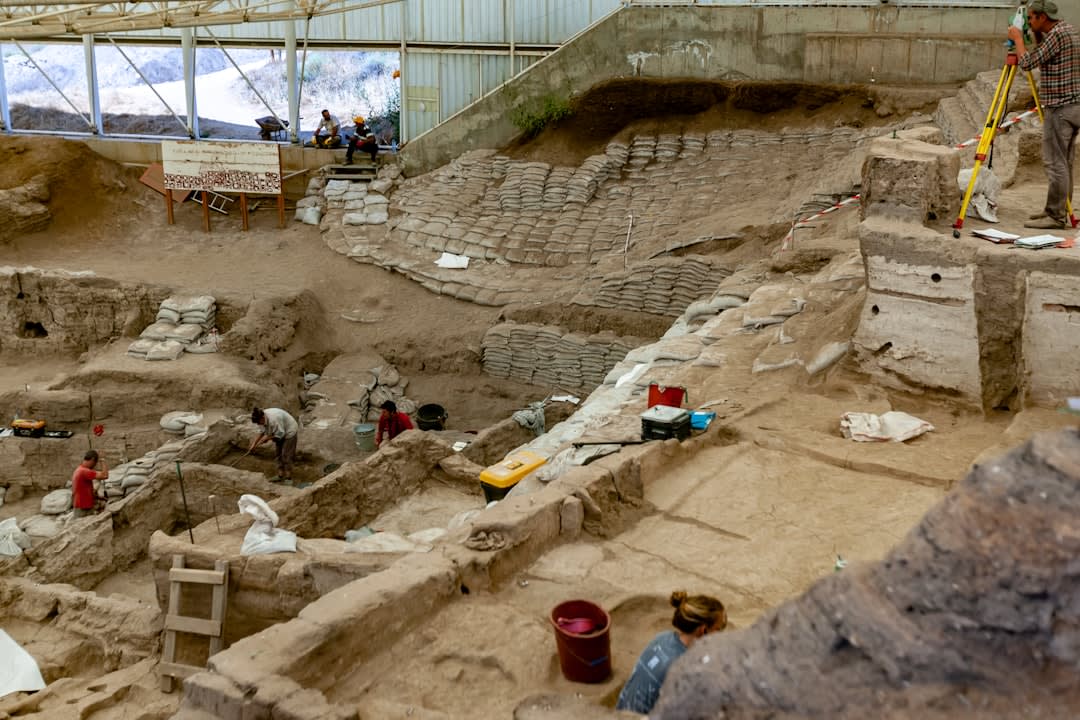 Weathered stone fragments and excavated tomb entrances near the royal necropolis of Ashur, scaffolding visible from ongoing conservation work