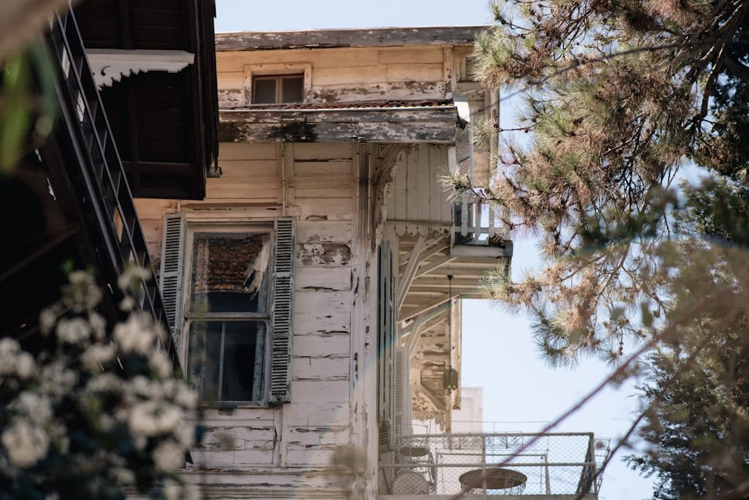 A row of traditional wooden mashrabiya balconies overhanging a narrow Basra canal, some restored and painted, others weathered and sagging with age