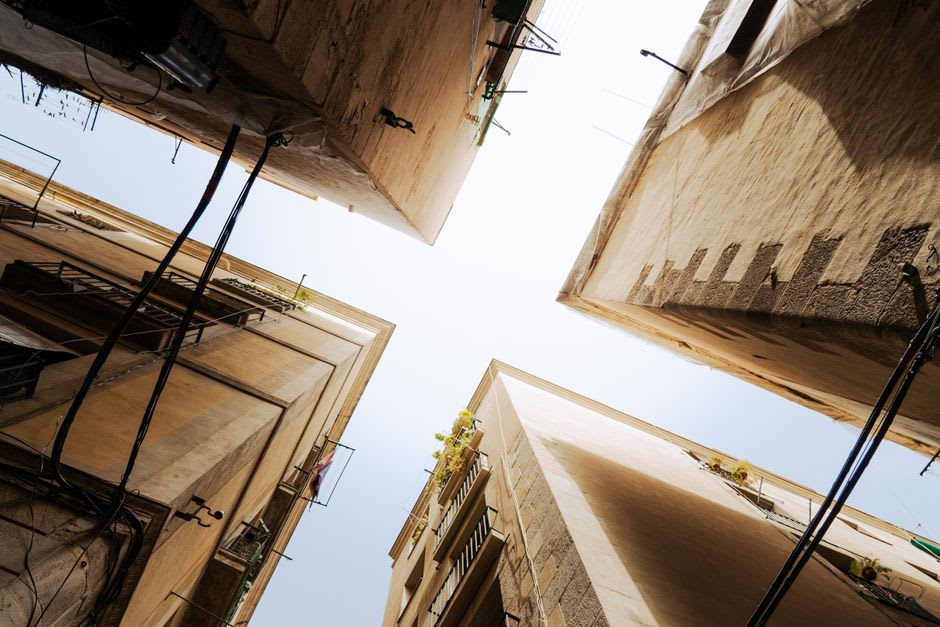 The mudbrick houses and narrow alleyways of Kirkuk Citadel's old quarter, some restored and inhabited, others crumbling and empty, the Prophet Daniel shrine visible at the summit