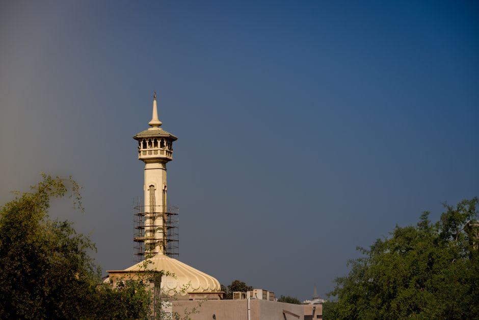 Stonemasons working on the reconstruction of the leaning minaret of the Great Mosque of al-Nuri in Mosul, traditional tools and cut stone blocks visible around the scaffolded structure