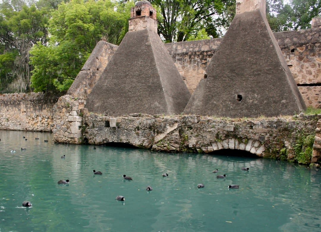 The still water of Laguna de Atezca ringed by misty pine forest near Acaxochitlán