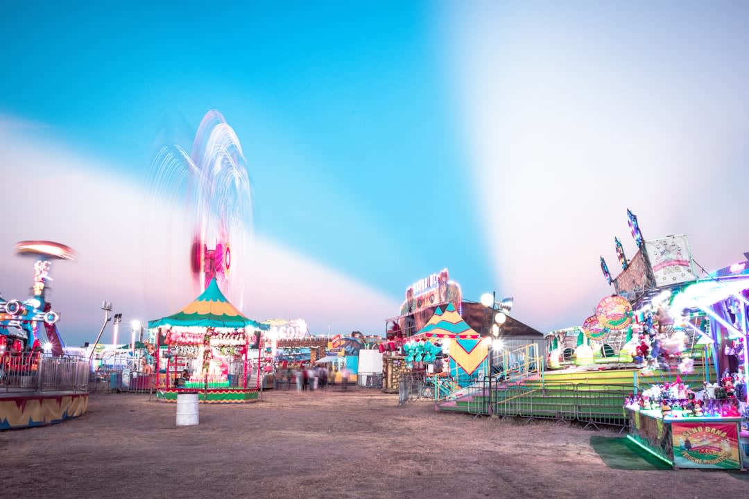 The Jardín de San Marcos during Aguascalientes's annual fair, the colonial garden packed with festival-goers under the lights, food vendors and musicians, the old laurel trees strung with colored lights above