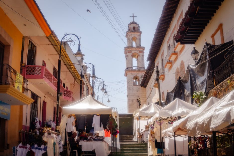 Morning market on the plaza in Ahuacatlán, produce stalls and clay pots in front of the colonial church facade