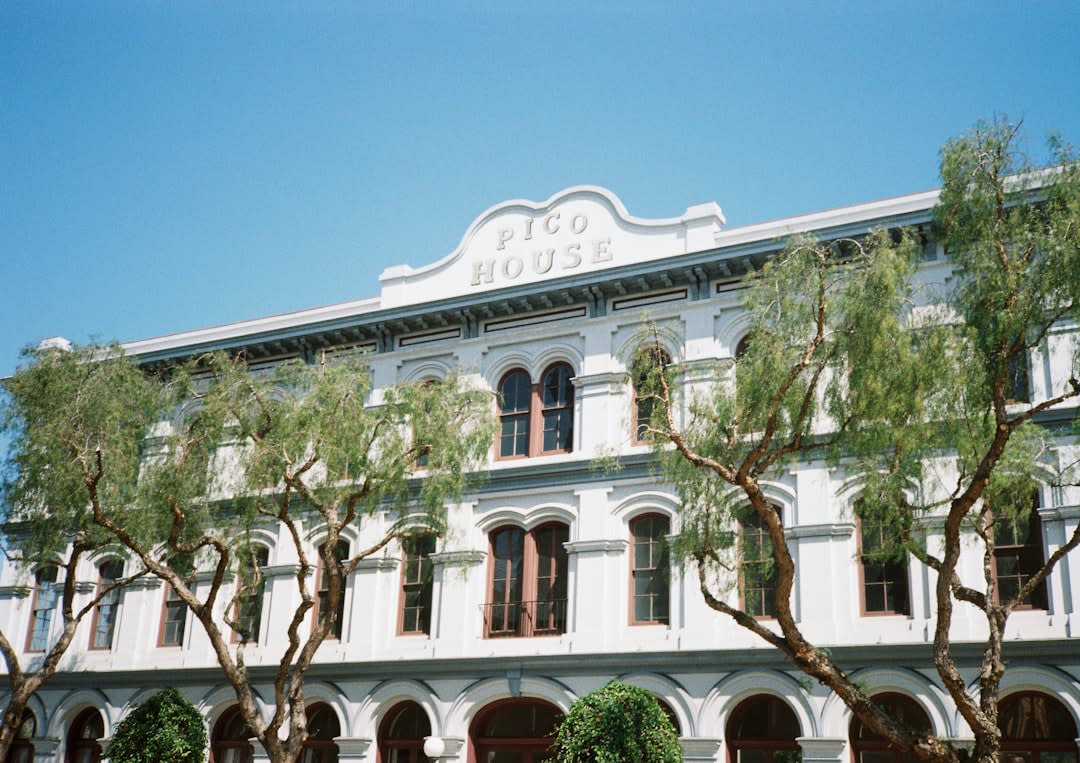 The whitewashed colonial mansion facades around the Álamos plaza, their heavy wooden doors and ornamental ironwork windows restored to their 18th-century character, bougainvillea on the walls and the church tower visible above