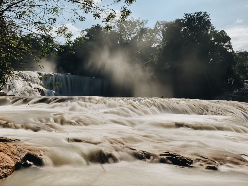 El Aguacero waterfall plunging into a limestone canyon pool surrounded by tropical forest