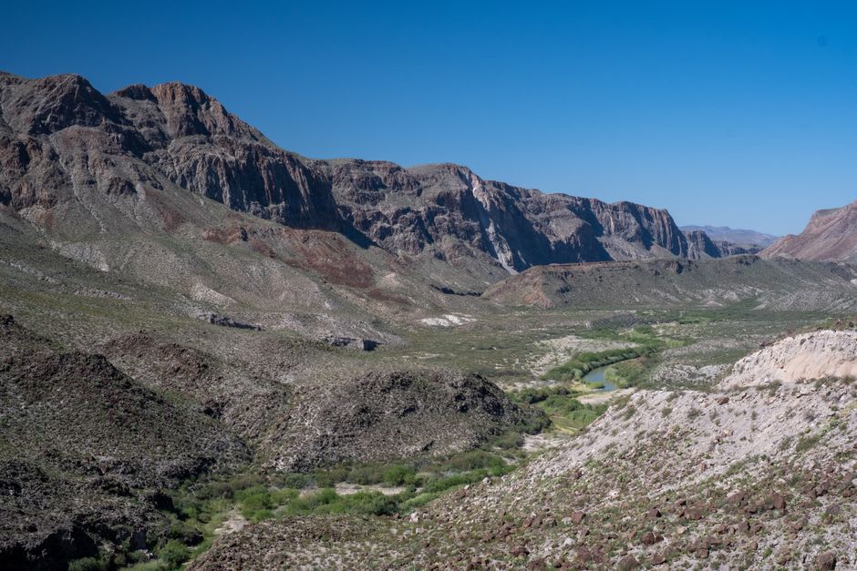 The Sierra del Carmen canyon walls casting long late-afternoon shadow across the Rio Grande at Boquillas, the water gone dark under the cliff face