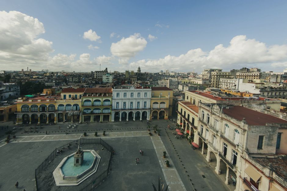 The quiet central plaza of Bustamante with its colonial fountain, the limestone sierra visible on the horizon, an orange tree in bloom at the corner