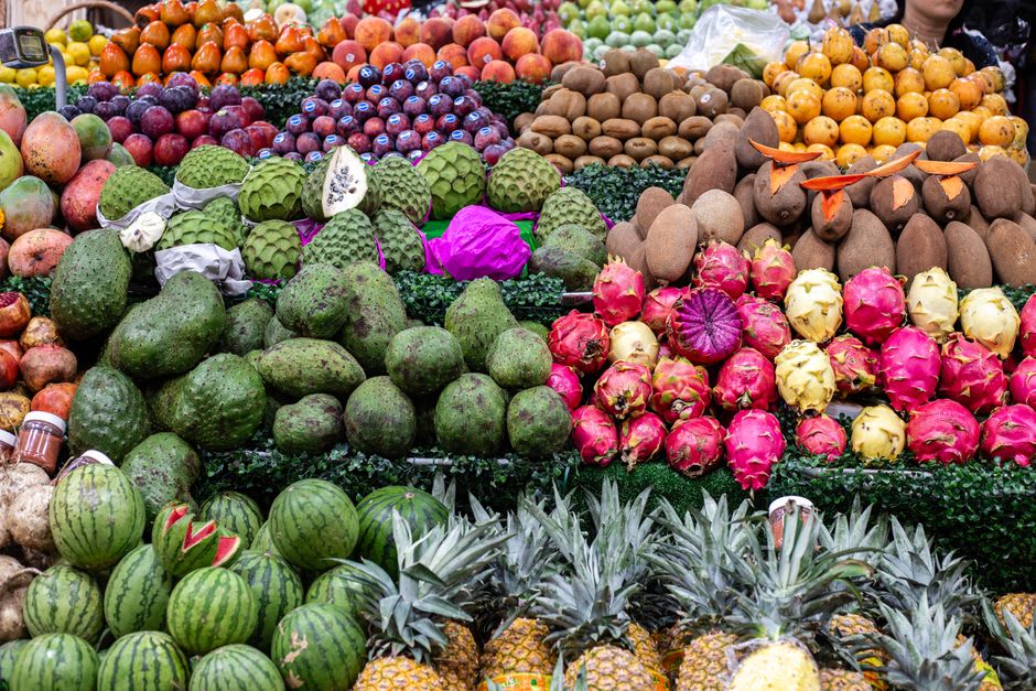 Stalls at the Calvillo market with guava products arranged in rows — golden ate de guayaba slabs, candied fruit, small jam jars — in the late morning light
