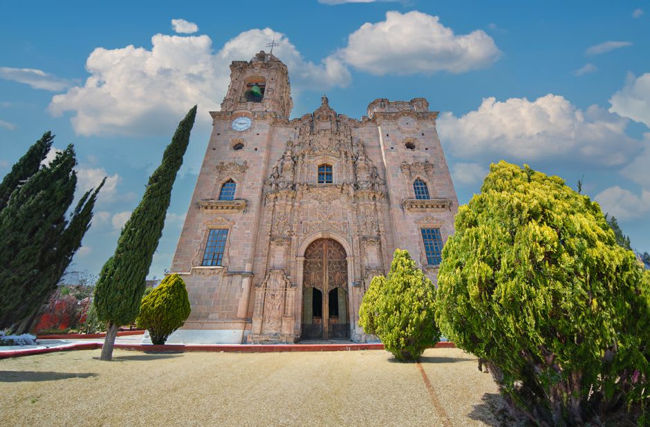 Interior of the Parroquia de la Purísima Concepción in Candela, stone walls and ochre vault lit by afternoon light through narrow windows