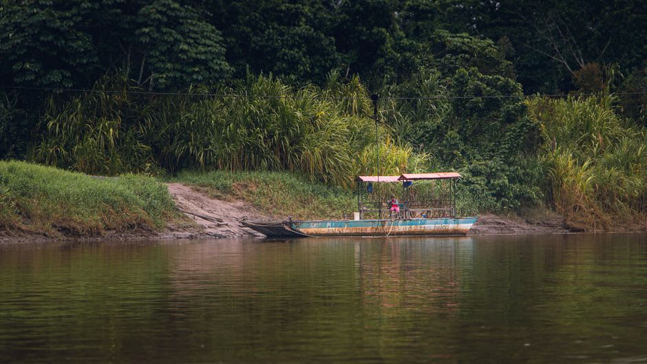 Wooden panga drifting on the Río Candelaria at dawn, dense jungle reflected in still dark water on both banks