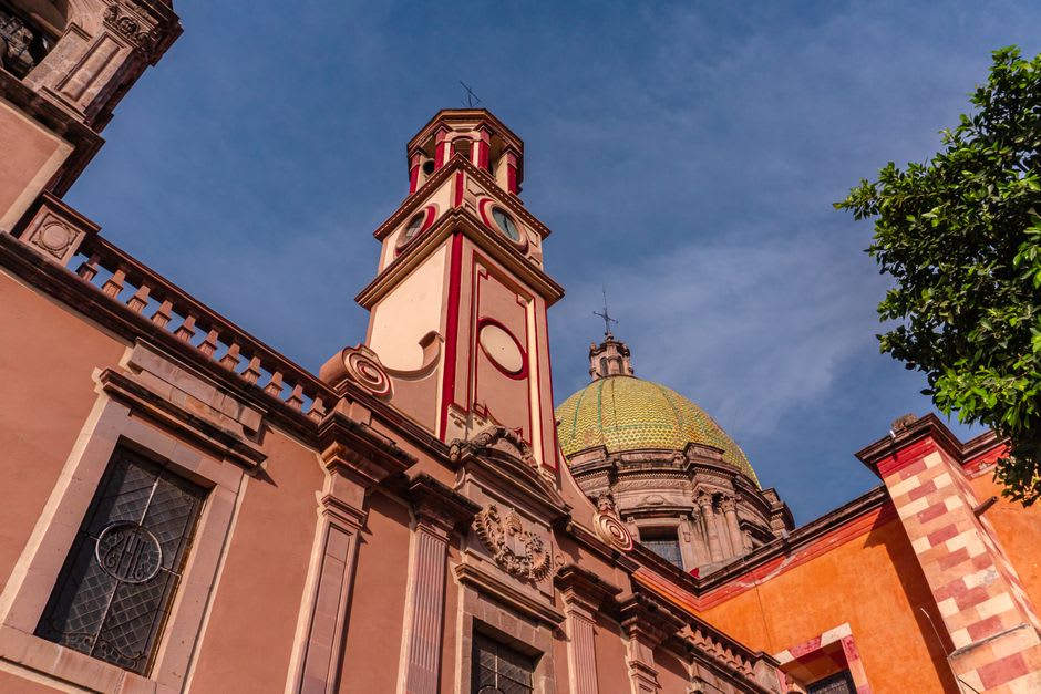 The pale neoclassical interior of the Templo del Carmen in Celaya, its luminous dome visible above the nave