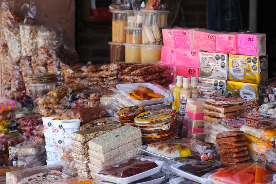 Copper cazos filled with amber cajeta at a Celaya market stall, the caramel thick and slow-moving in the morning light