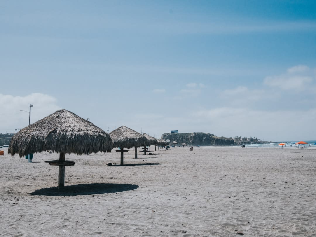 The white sand beach at Celestún, a palapa restaurant and fishing boats on the Gulf of Mexico side, the flat Yucatán horizon beyond, afternoon light on the calm water