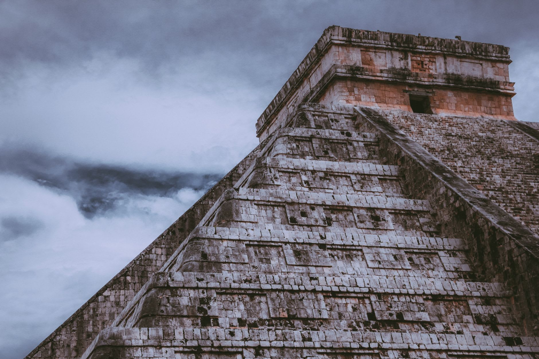 El Castillo pyramid at dawn, with the eastern staircase lit and long shadows falling across the grass below