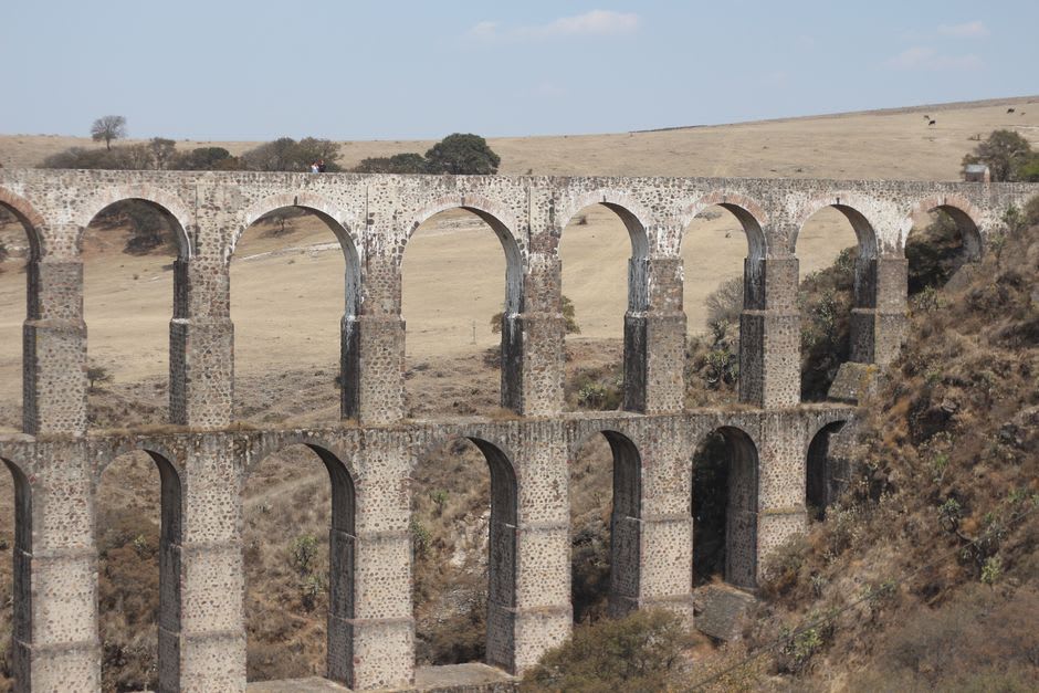 Irrigation canals cutting through dry farmland near Chilcuautla, a thin ribbon of green crops against the pale arid soil of the Valle del Mezquital