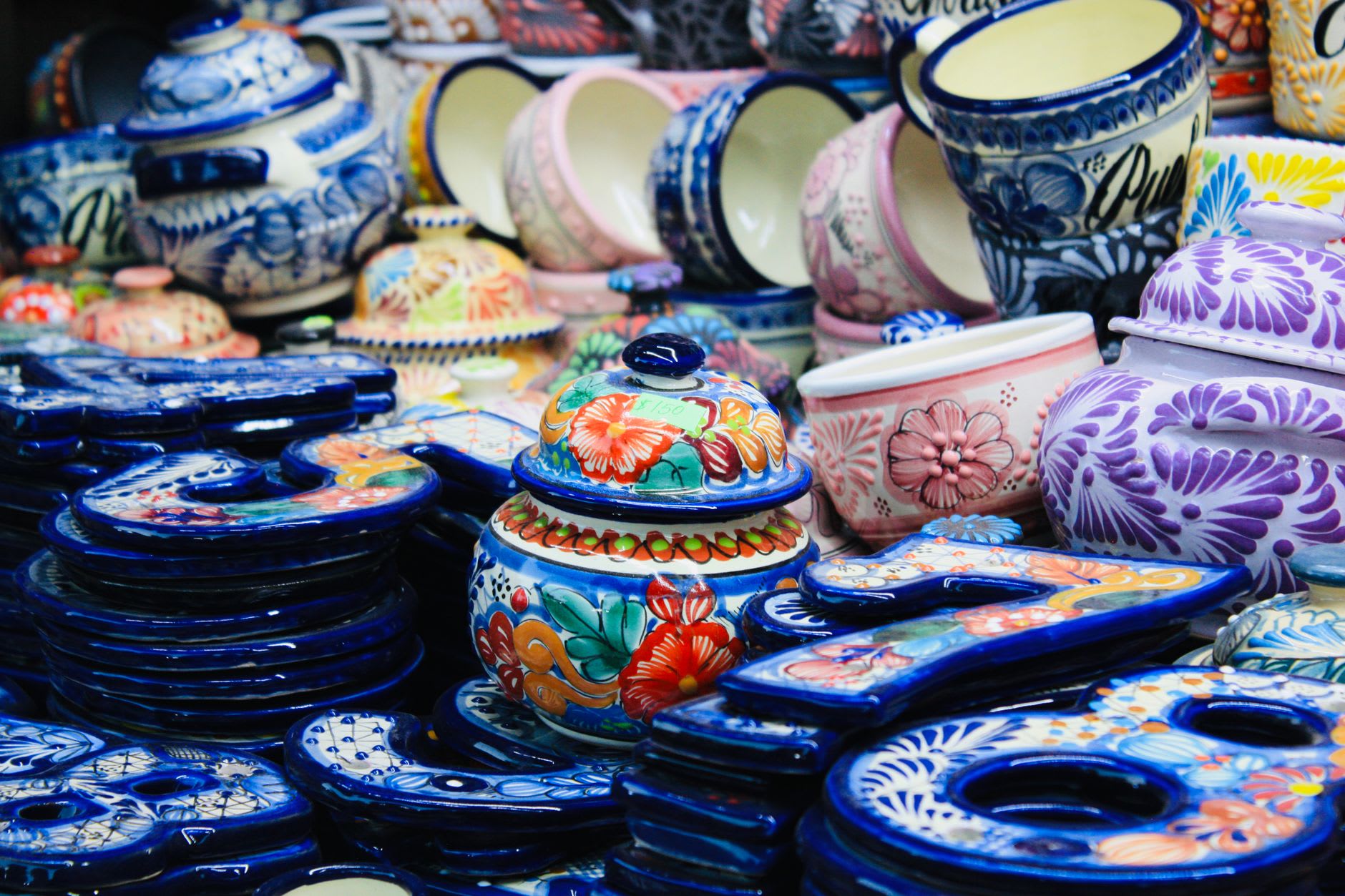 A Talavera pottery workshop in Cholula with hand-painted blue and white ceramic plates, tiles, and vases arranged on wooden shelves