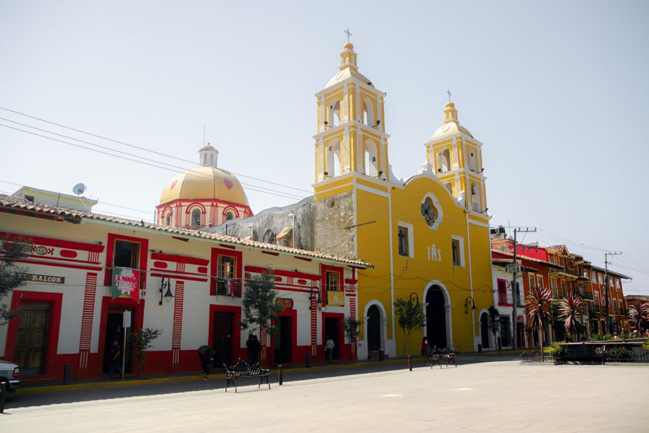 Market stalls in Coalcomán with produce, leather goods, and dry goods laid out under shade tarps