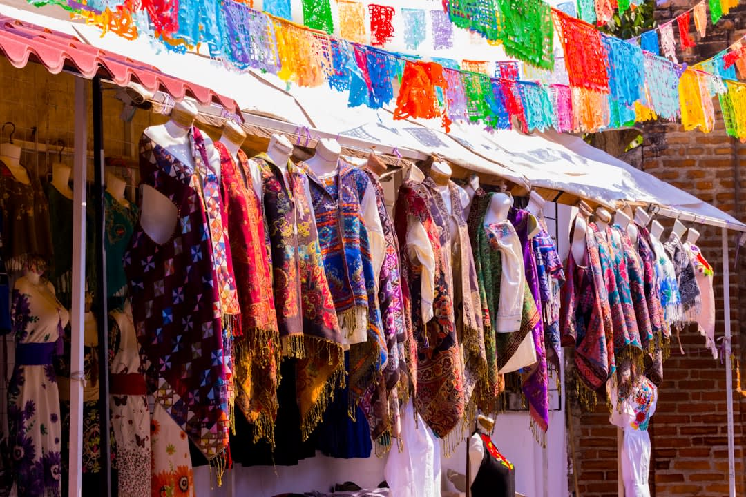 Tojolabal Maya women at the Comitán market, the embroidered blouses and woven textiles of the highland Chiapas indigenous tradition visible, the colonial arcaded building of the market behind them, the highland atmosphere of a city at 1,635 meters
