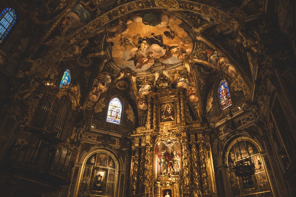 The interior of Cosalá's church of Santa Úrsula, baroque altarpiece visible in warm candlelight, stone columns framing the nave