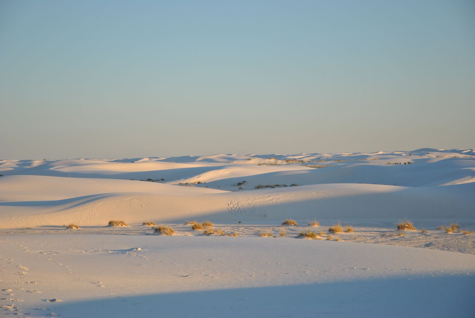 The white gypsum dunes of Cuatro Ciénegas at dawn, the turquoise pools visible in the valley below, the surrounding Chihuahuan Desert and the Sierra de San Marcos range behind, the specific white-against-blue of gypsum sand and desert sky