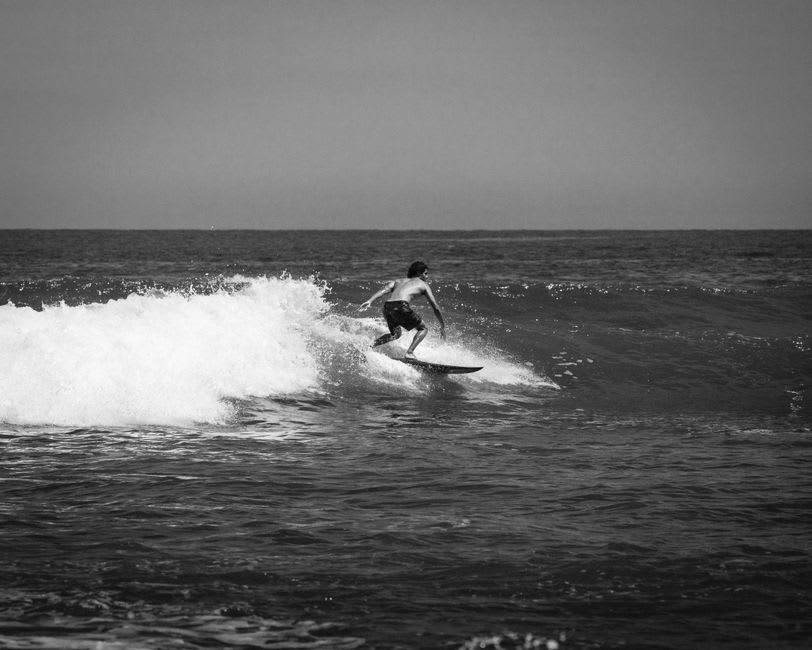 Pacific swell rolling into Playa Los Cerritos under a pale morning sky, with surfers scattered across the lineup