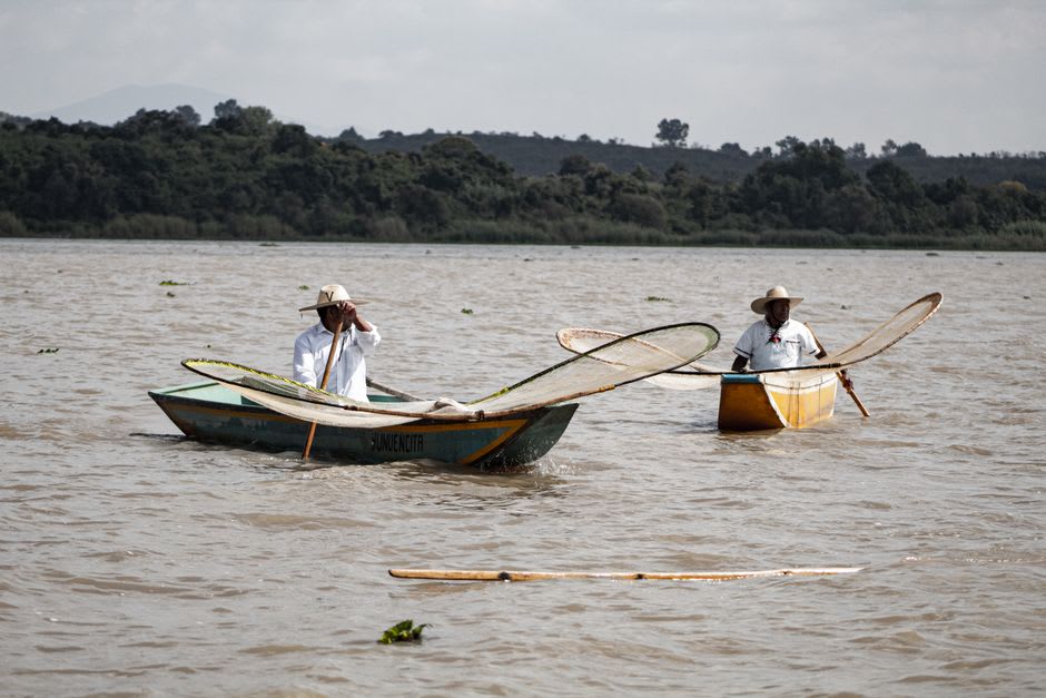 Fishermen working traditional butterfly nets from a canoe on the flat grey surface of Lake Patzcuaro near the Erongaricuaro dock