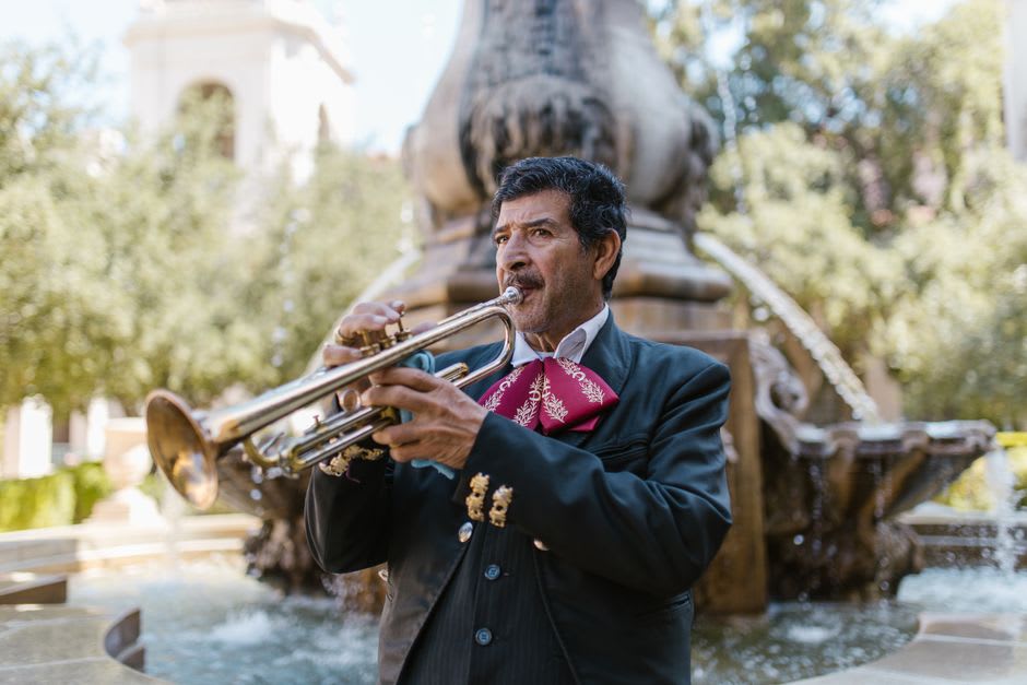 Mariachi musicians in full charro regalia playing together in the crowded plaza at night