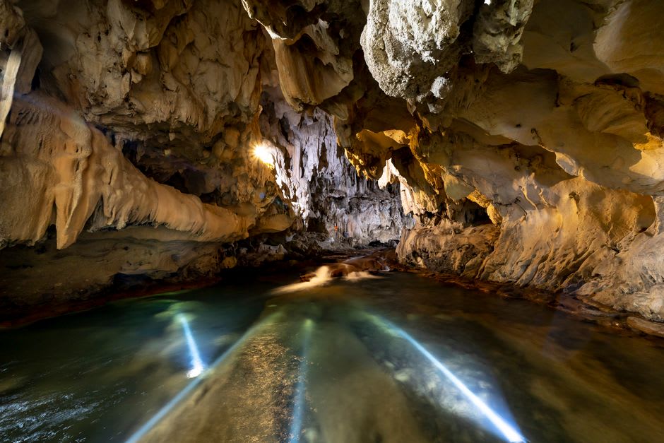 The entrance to one of the named chambers, with a group of visitors standing in silhouette against the illuminated cavern interior