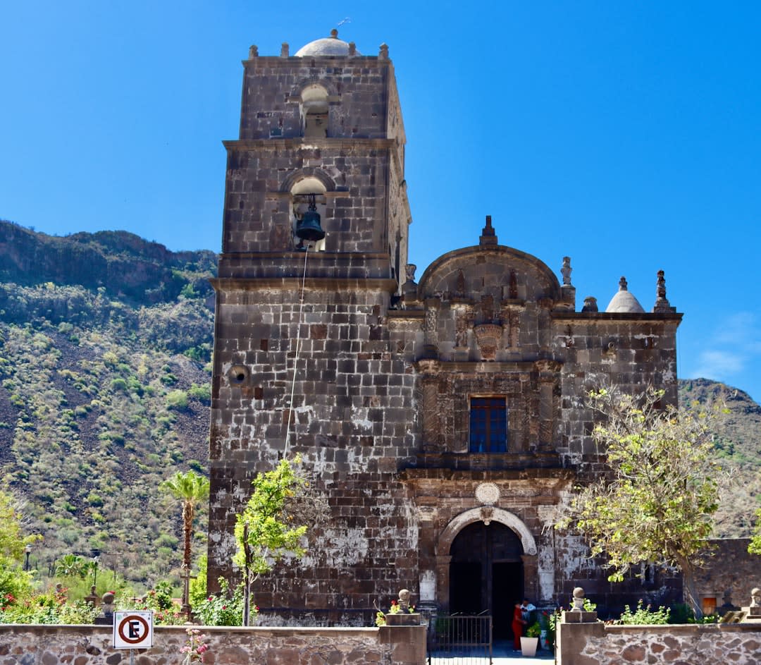 The restored colonial courtyard of Hacienda San Miguel Regla near Huasca de Ocampo, its 18th-century arched arcade and garden, the mountain of Hidalgo visible above the hacienda walls, the silver-era mining equipment in the forecourt