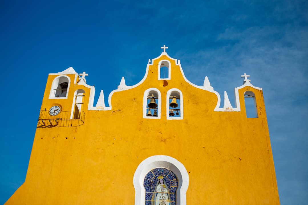 The golden-yellow atrium and arched portales of the Convento de San Antonio de Padua in Izamal, Yucatán, the wide enclosed courtyard where missionaries converted tens of thousands of Maya