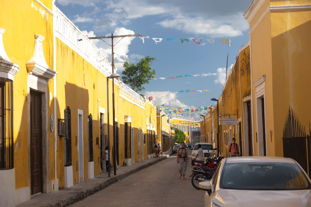The yellow rooftops of Izamal seen from the summit of the Kinich Kakmó pyramid, the convent of San Antonio de Padua visible above the uniform ochre cityscape, the Yucatán flatlands stretching beyond
