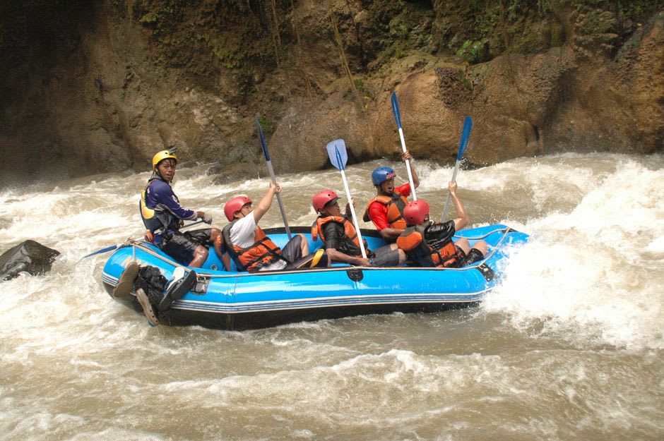 Rafts pulled onto a sandy bank at the canyon's edge, guides and passengers resting in the afternoon light