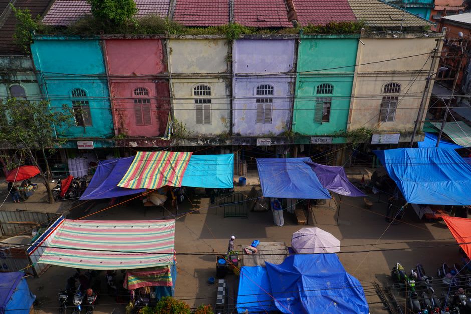 Rows of hand-woven palm petate mats and baskets stacked against a wall at a market stall in Jojutla