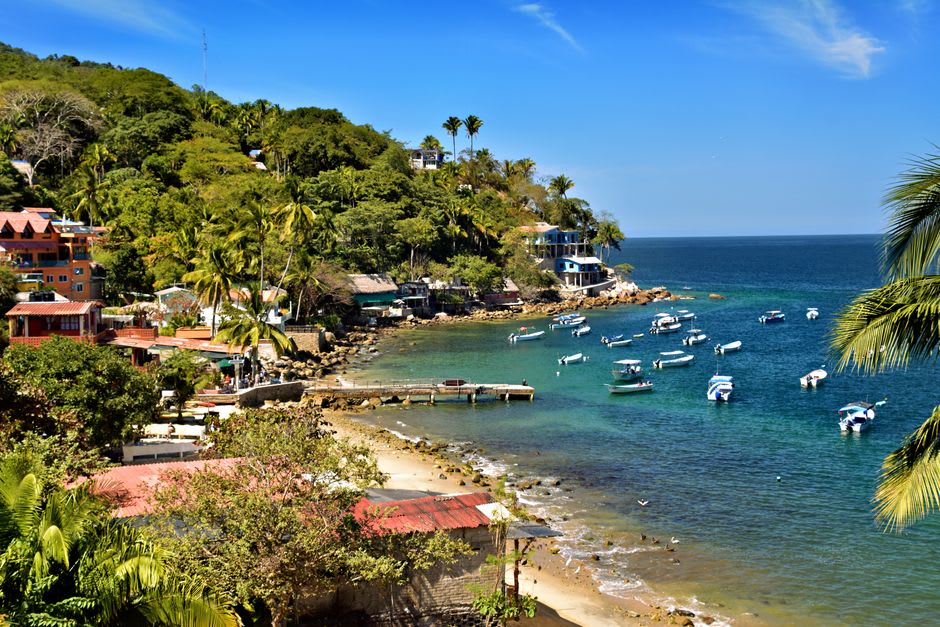 Wide view of La Manzanilla bay at dawn, calm water reflecting a pale sky before the wind arrives