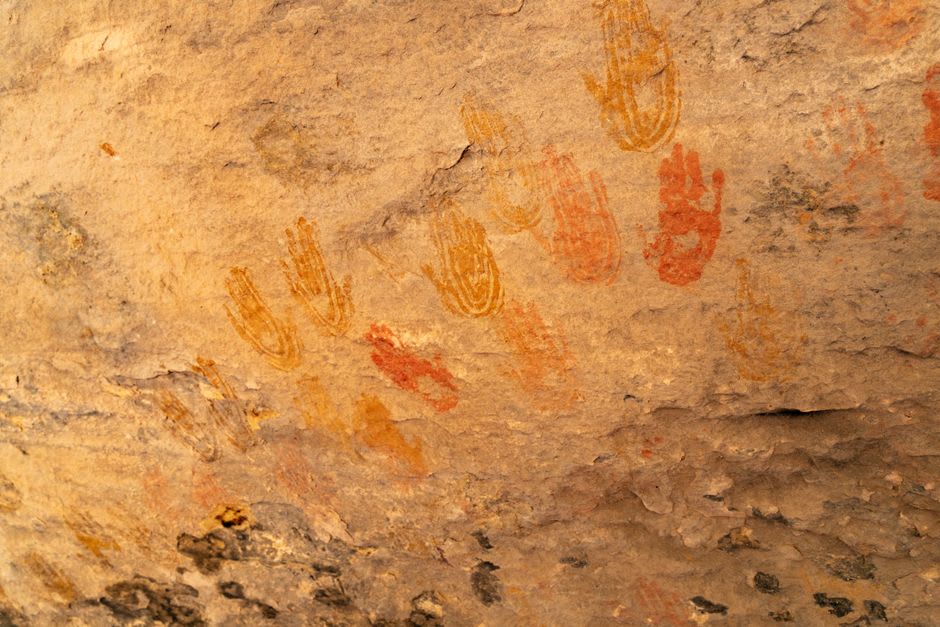 Ancient Maya bas-relief carving of a warrior figure and dark handprints preserved on limestone cave walls deep inside Grutas de Loltún