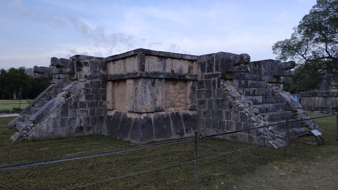 The carved stone eagle at the entrance to the Cuauhtinchan temple at Malinalco, the living rock carved into the eagle warrior form, the circular temple chamber visible through the entrance, the rock face and subtropical vegetation of the canyon above